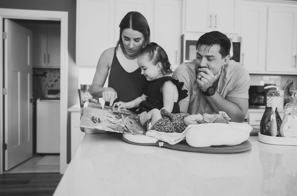 Family members gathered around table doing activities together in black and white.