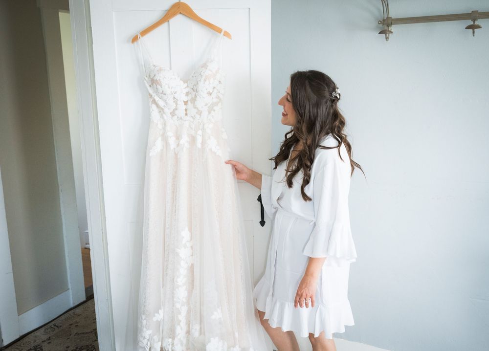 White wedding dresses hanging on display in a minimalist dressing room setting.
