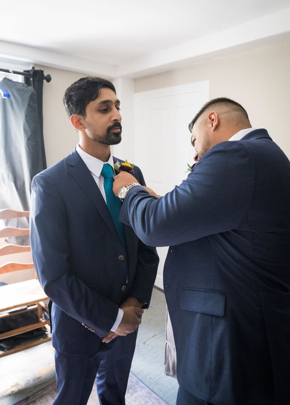A series of images showing a groom getting help with adjusting his suit and tie before the wedding ceremony.