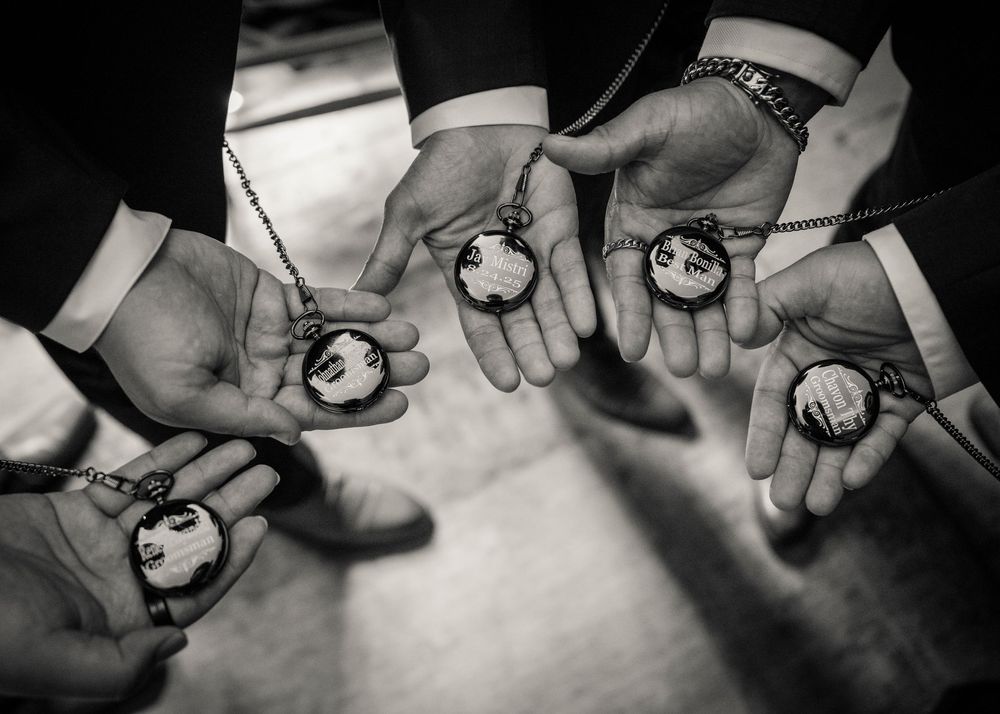 A close-up black and white series of hands holding stones on a white surface.