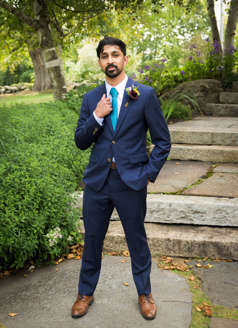 Series of shots showing person in navy blue suit posing playfully in garden setting.