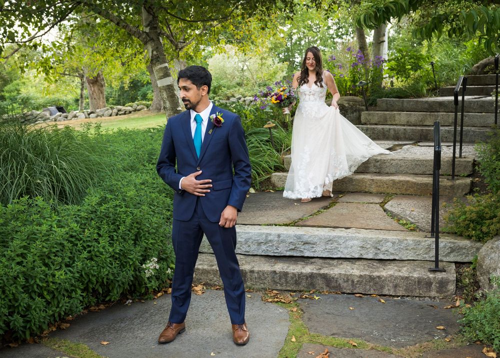Wedding couple walking along stone pathway surrounded by green garden landscaping.