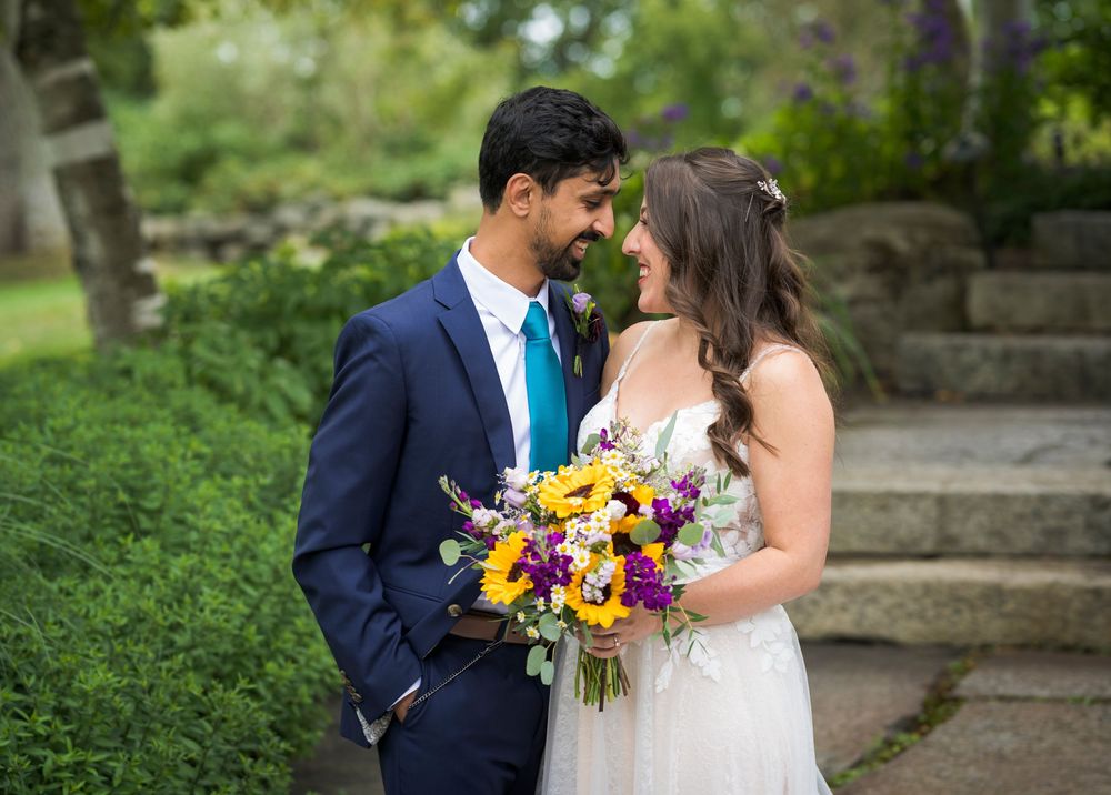 Outdoor wedding photos of a couple in a garden setting with colorful floral bouquet.