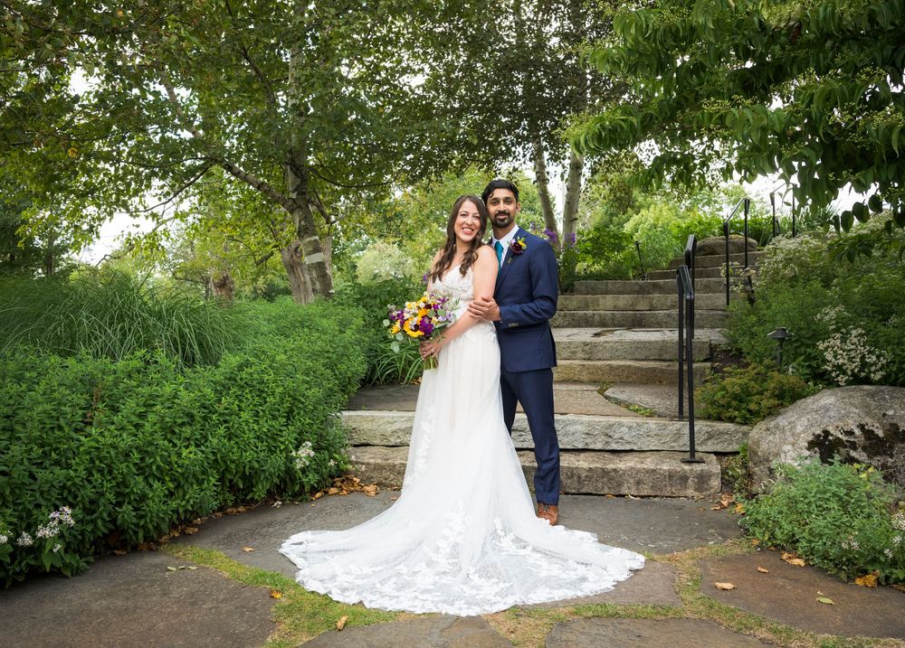 Garden wedding photos showing couple posing along stone steps surrounded by lush greenery.