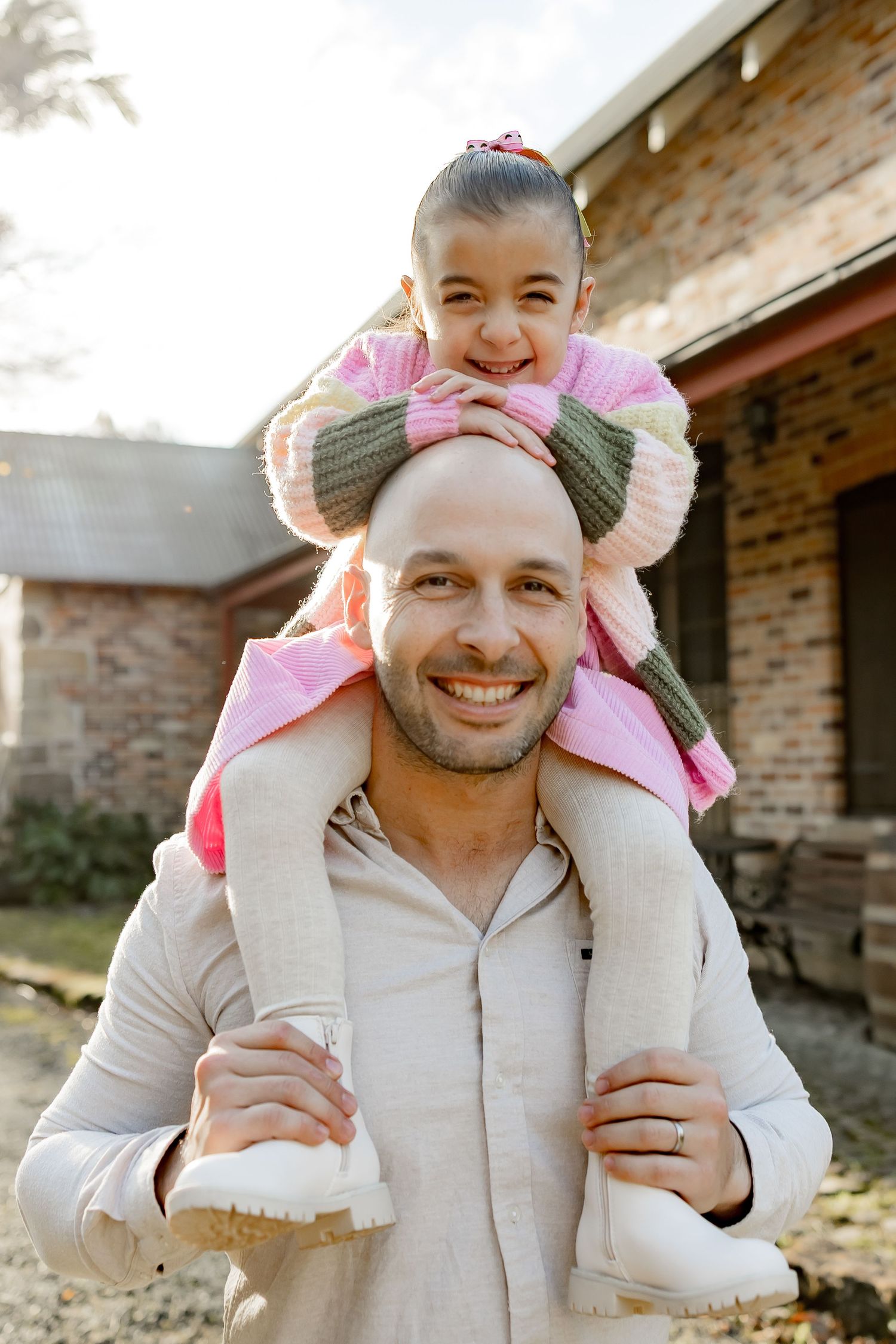 A joyful family moment captured outside a brick house on a sunny day.