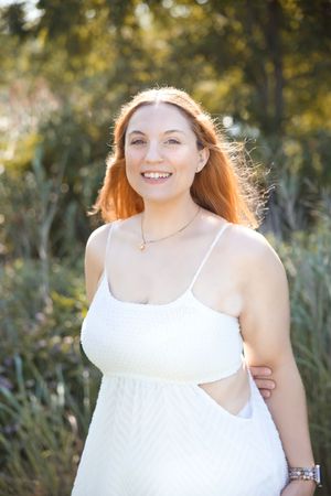 A joyful moment captured in a white summer dress against a natural outdoor setting with warm sunlight.