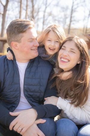 A joyful family shares a candid moment together outdoors on a sunny day, laughing and embracing.