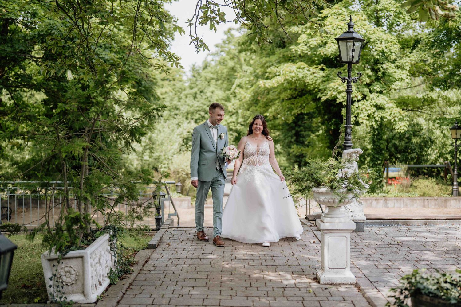 Wedding ceremony location with stone pathway and decorative lanterns under green trees.
