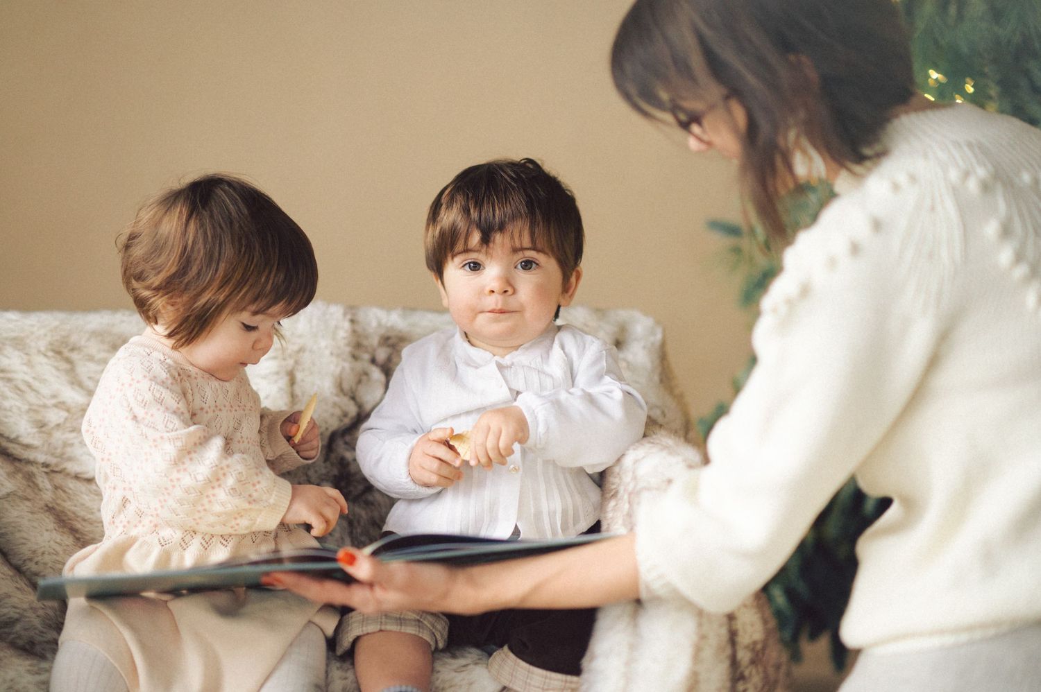 Family sits together on couch reading a story from a tablet device in a cozy living room setting.