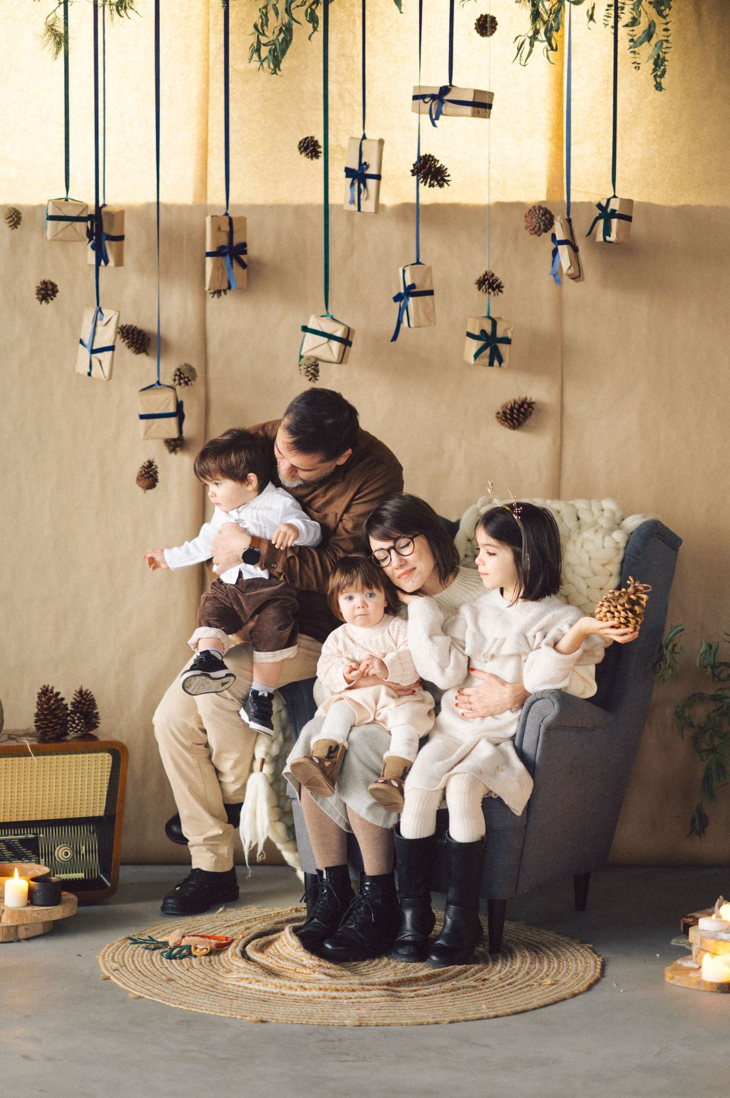 Cozy winter scene with string decorations hanging from ceiling and warm knit clothing on gray armchair.