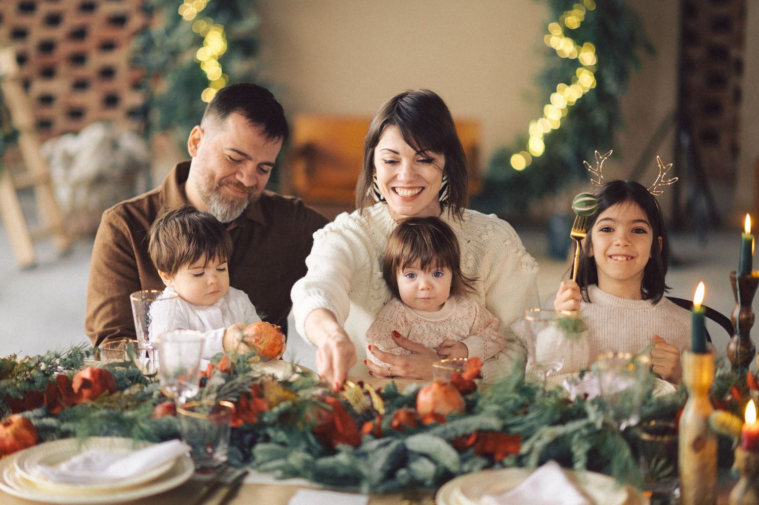 A family gathers around a festive Christmas dinner table with decorations, food, and glowing candlelight.