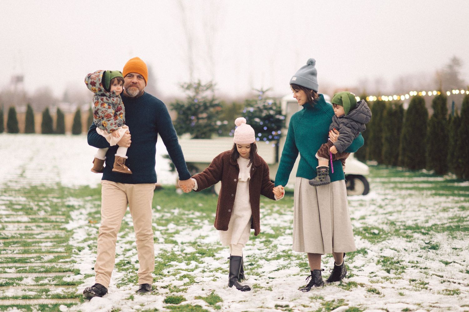 People walking together on a snowy ground in winter clothing with trees and hedges in the background.