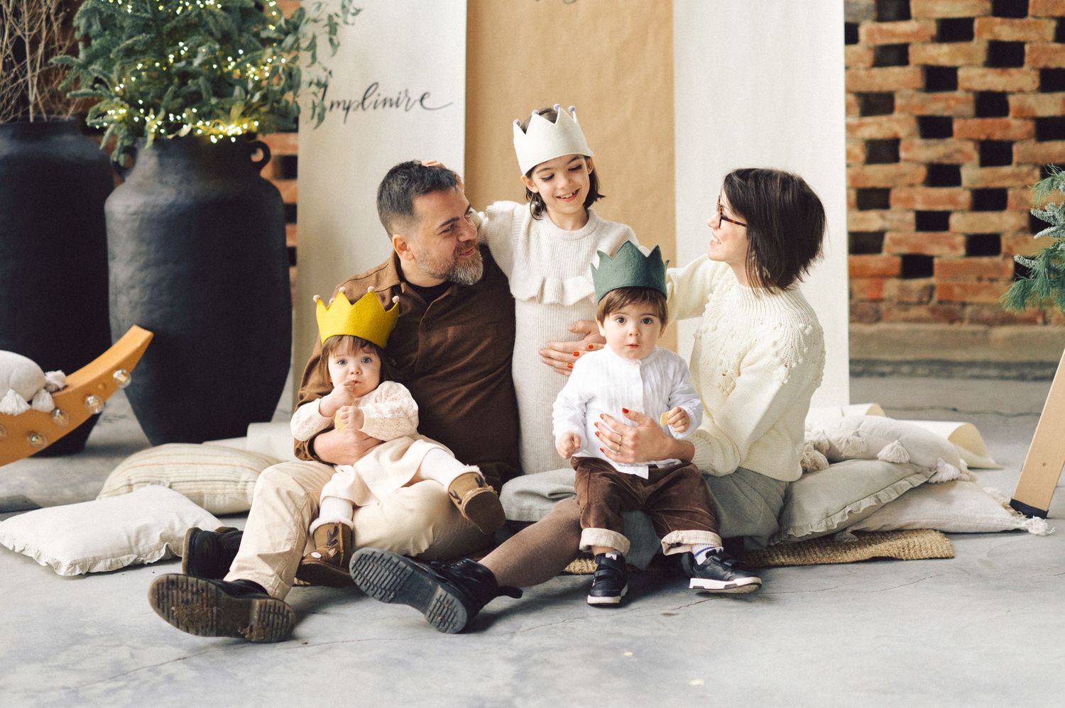 Three black and white photos show a cozy family moment together sitting casually on wooden floor near a wall.