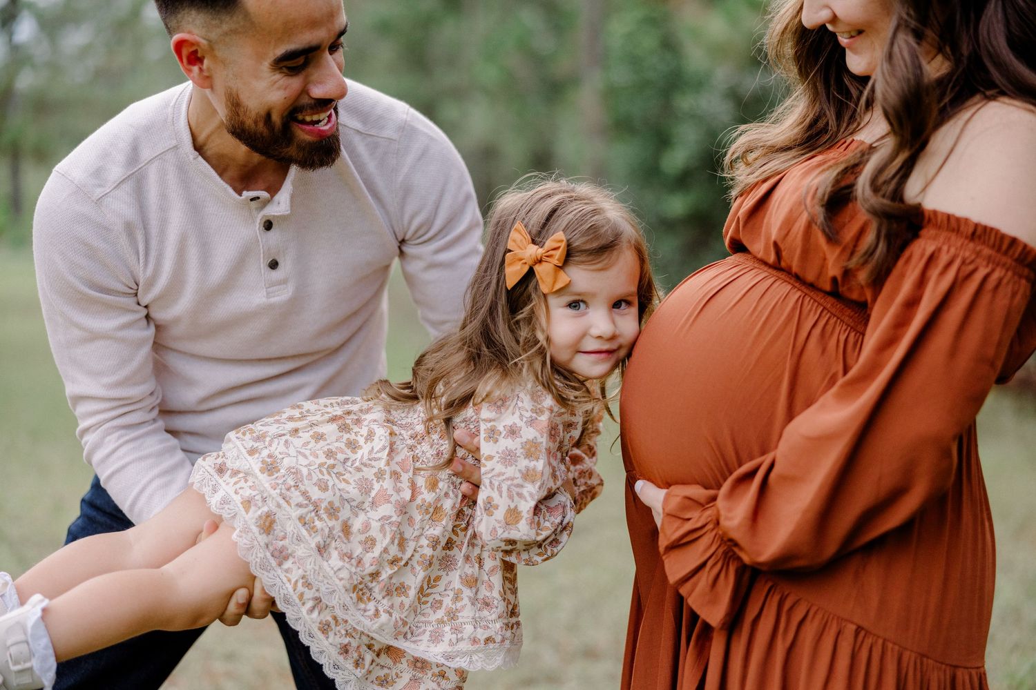 A happy family enjoys quality time together outdoors wearing coordinated rust and cream colored outfits.