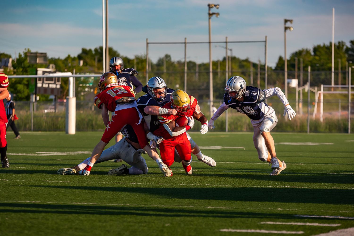 Five motion-blurred action shots show dramatic tackles during an intense football game on a sunny grass field.