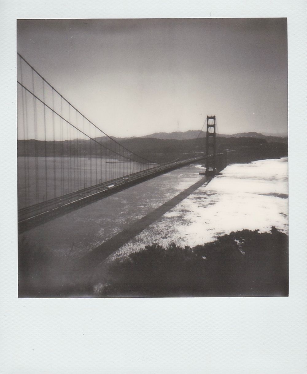 Dramatic black and white photograph of the Golden Gate Bridge stretching across the foggy bay.
