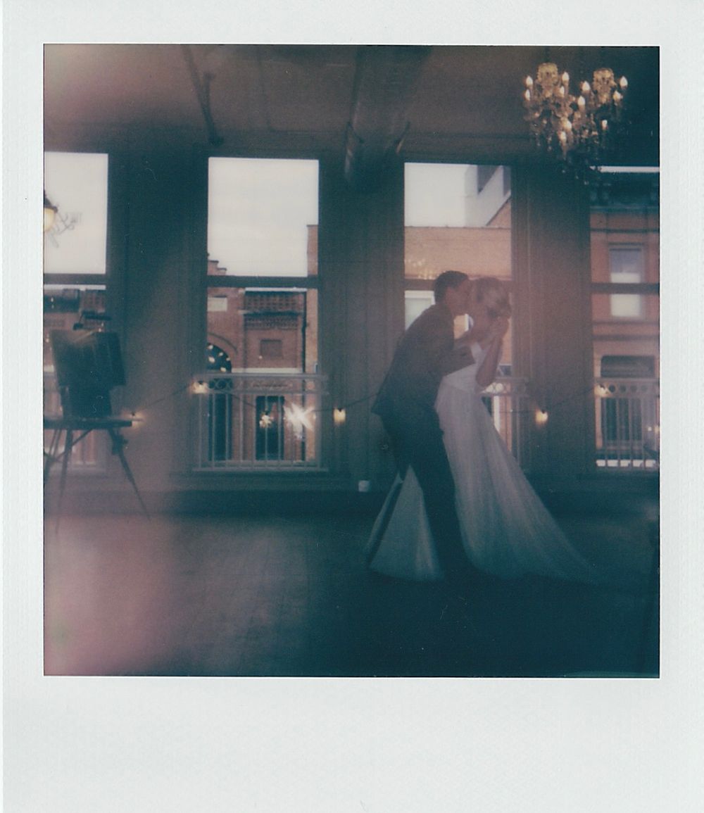 Blurred silhouettes of people dancing in a dimly lit reception hall.