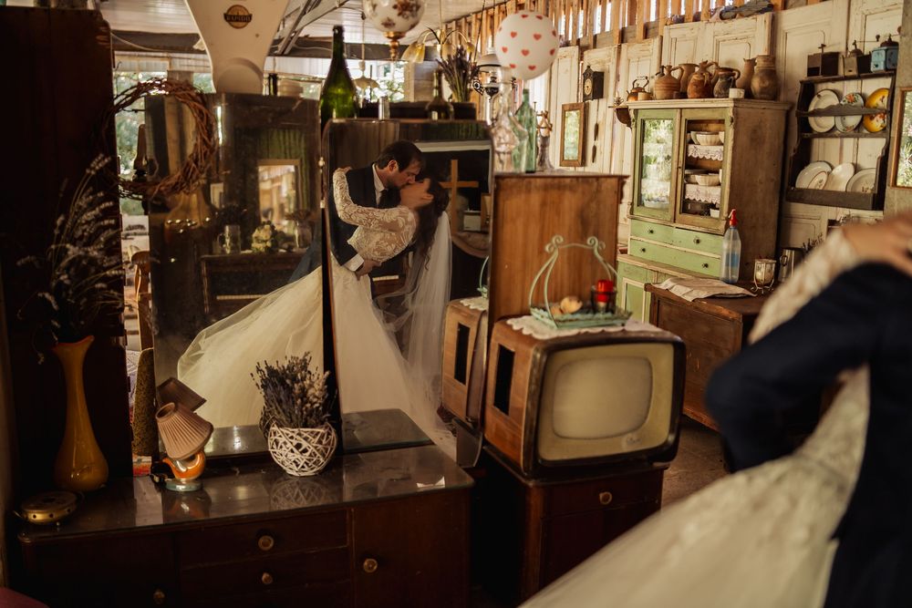 Vintage antique shop interior with old television set, glassware, and wooden furniture in warm lighting.