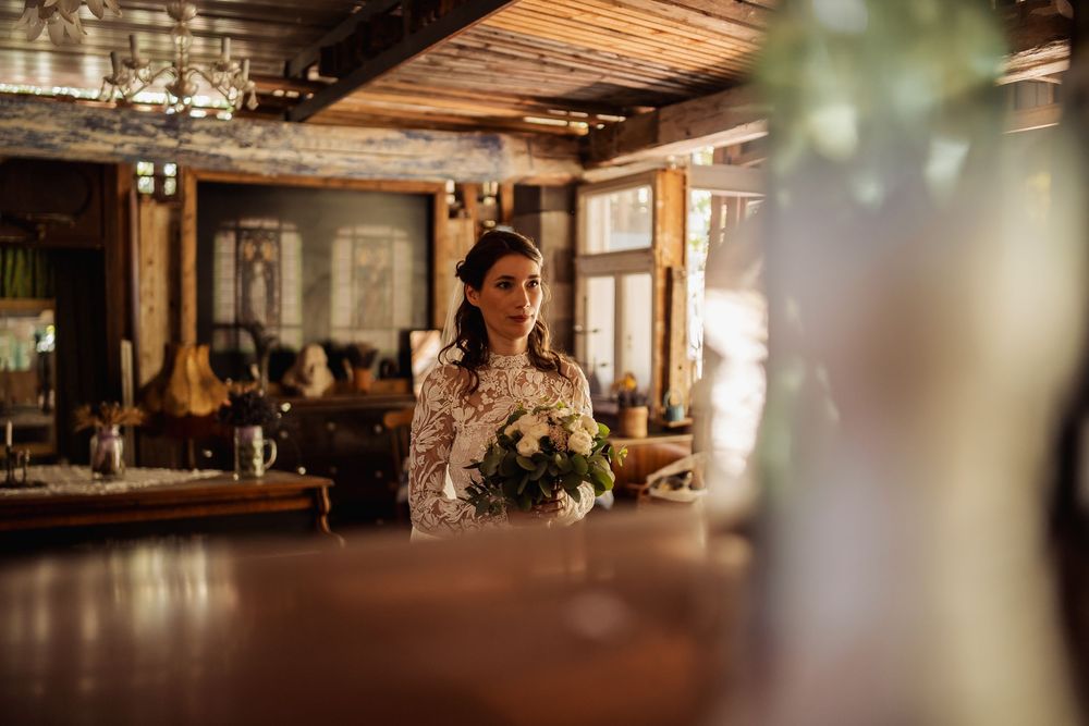 Rustic wooden beams and exposed ceiling in a dimly lit restaurant space create a warm, industrial atmosphere.