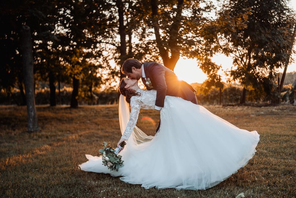 Golden sunset light illuminates happy couple embracing in beautiful garden setting during romantic photoshoot.