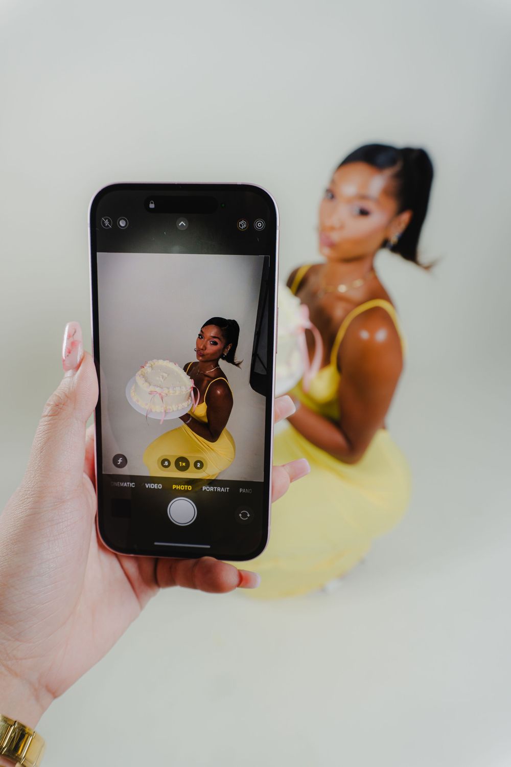 Hand holding phone to capture professional photoshoot in studio setting.