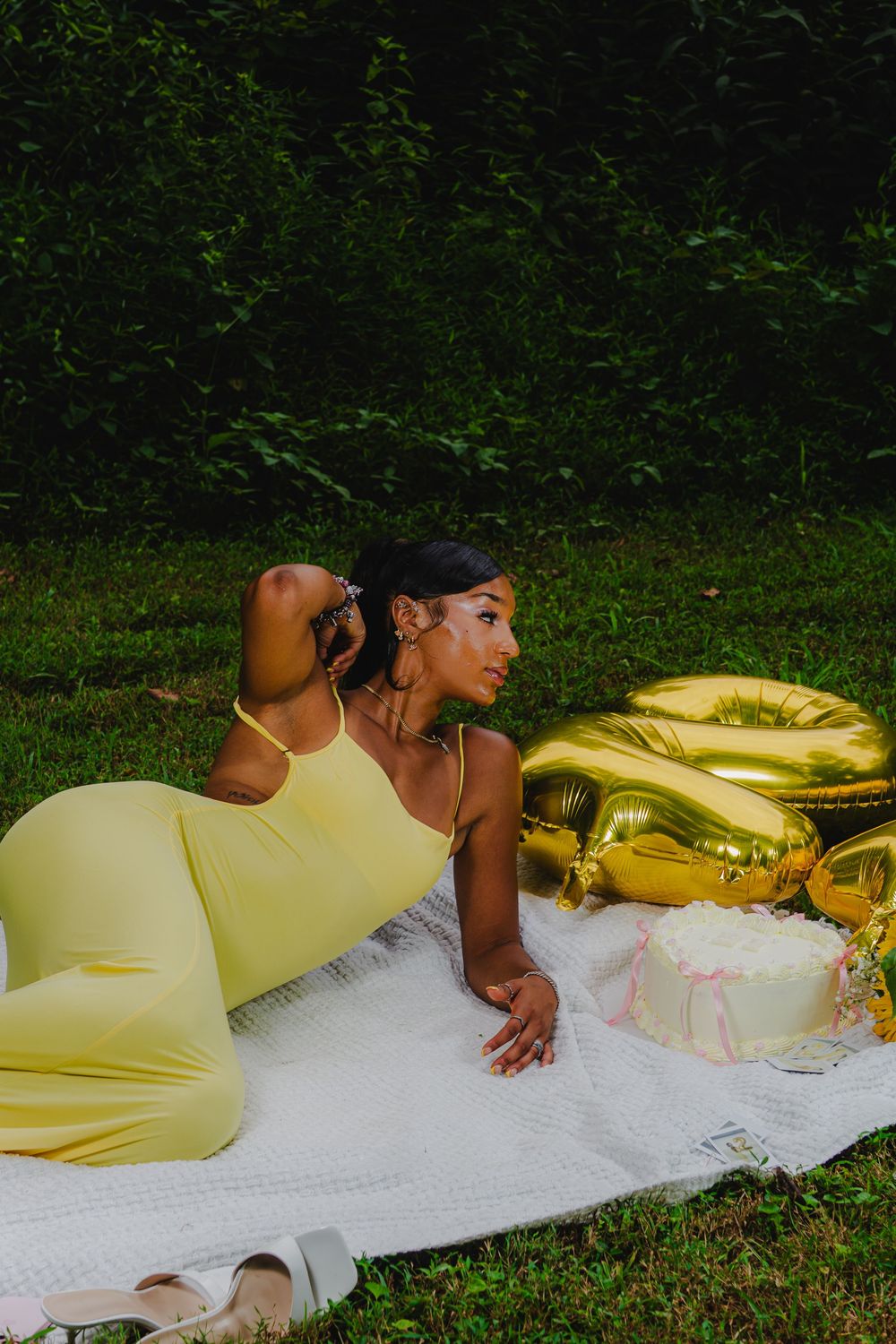 Outdoor photoshoot on white blanket with yellow dress and golden decorations.
