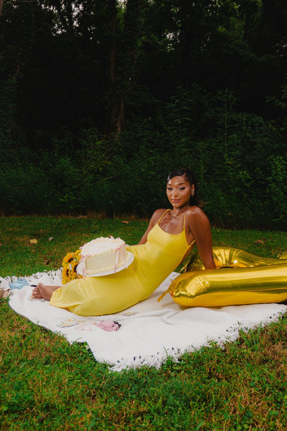 Outdoor photo arrangement with yellow dress and decorative elements against forest backdrop.