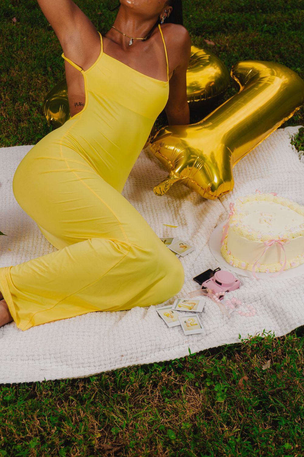 Artistic composition with yellow dress and decorative elements on white blanket outdoors.