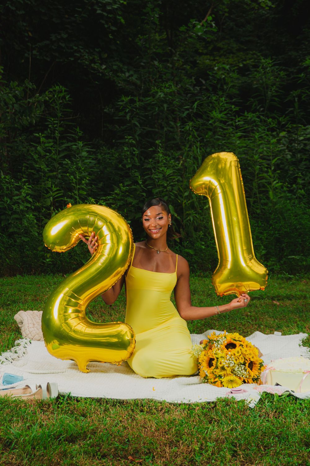 Birthday celebration photoshoot with gold number balloons, yellow dress and sunflowers.