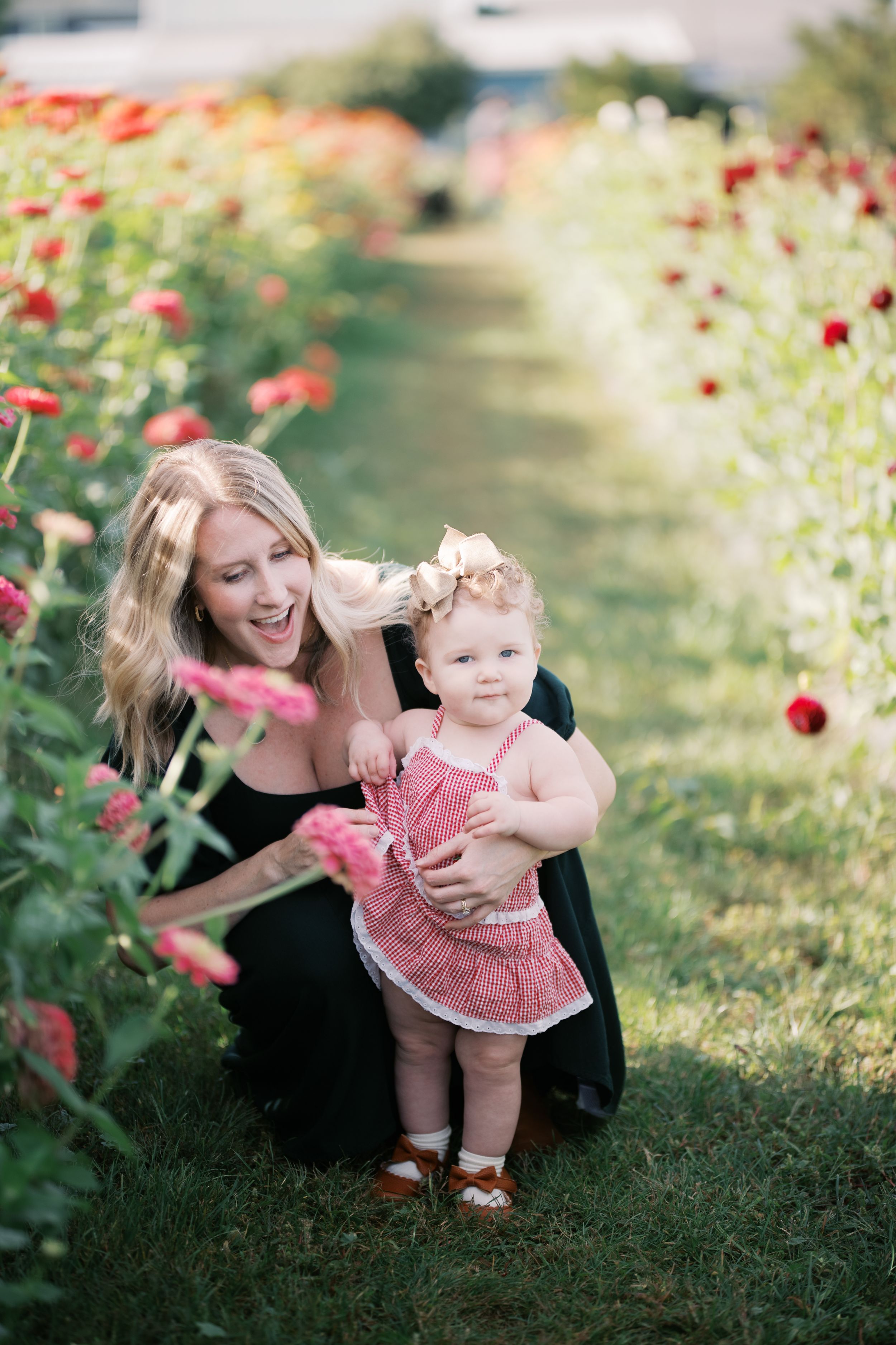 Sweet outdoor photoshoot in a garden with red flowers and greenery showing playful interaction in summer light.