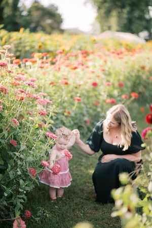 Two figures share a tender moment among vibrant pink zinnias in a lush garden.