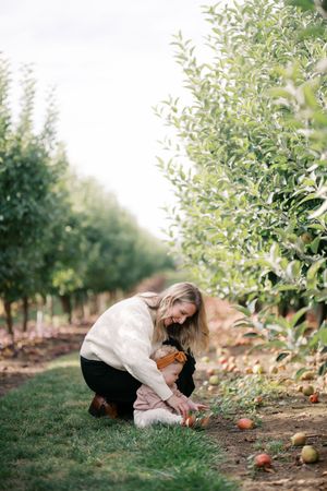 A heartwarming autumn scene showing a tender moment between two figures in an apple orchard.