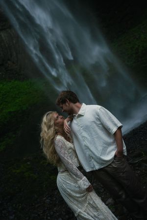 Couple looking into each other's eyes with the Latourell Falls behind them at an Oregon engagement photoshoot