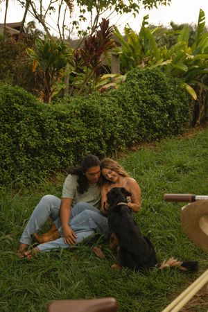 Adventurous couple riding bikes through a lush forest in Kauai, Hawaii during their engagement session with their dog