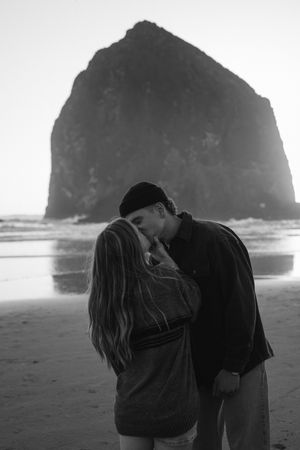 Couple kissing on Canon beach in Oregon at sunset for their engagement photoshoot