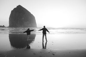 Couple dancing on Canon beach in Oregon at sunset for their engagement photoshoot