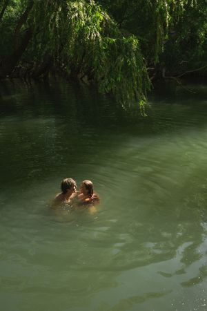 Adventurous couple swimming in the green lake in southern utah for a fun engagement session