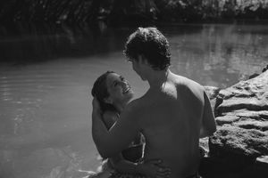 Carefree couple playing in the water of a Utah lake during summer photoshoot