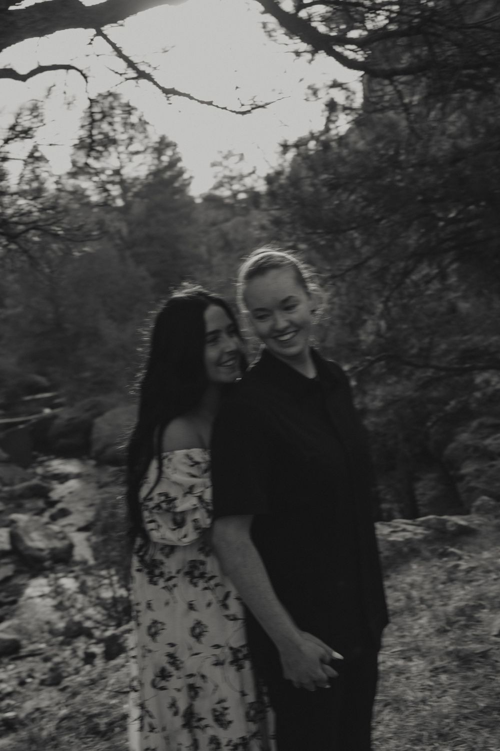 Lesbian couple holding hands and laughing in the utah mountains during an engagement photoshoot