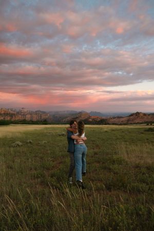 Couple engagement session at a field in Zion National Park with pink and purple sunset
