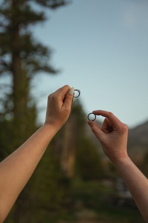 Lesbian couple holding up their rings to the sky during a Southern Utah engagement photoshoot