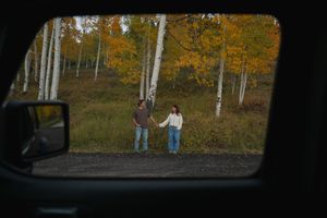 Autumn engagement session on Cedar Mountain in Utah with golden fall foliage captured through a jeep door