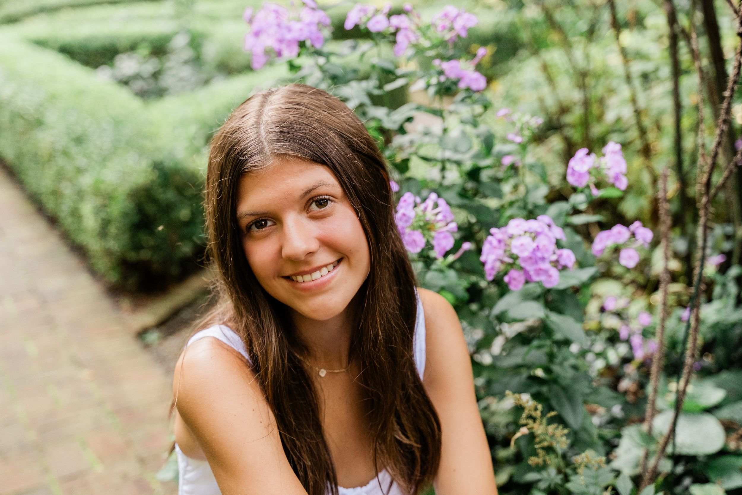 Someone relaxes in a garden surrounded by vibrant purple wildflowers on a sunny summer afternoon.