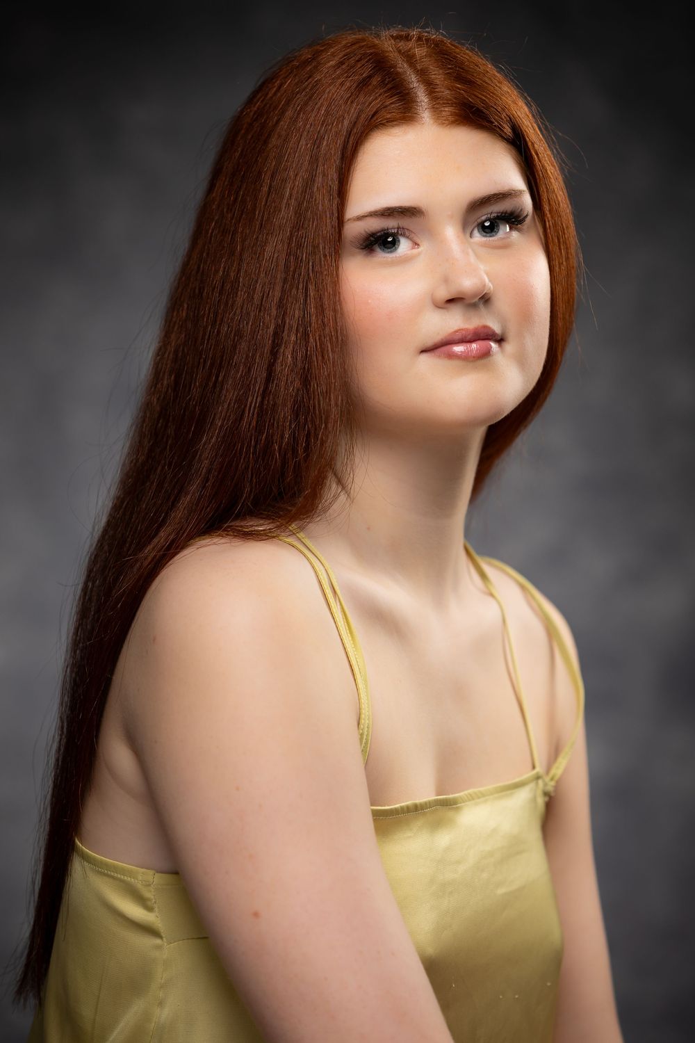 A woman with auburn hair poses in a gold satin camisole against a dark background in a series of portrait shots.