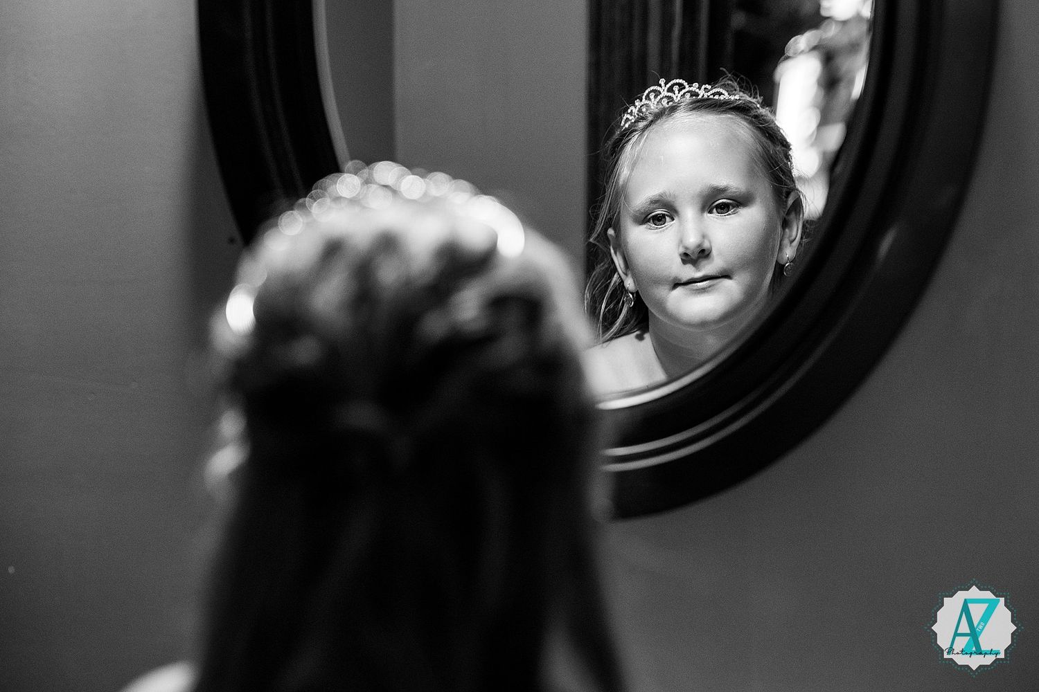 Black and white reflection captured in an ornate round mirror showing elegant attire and accessories.