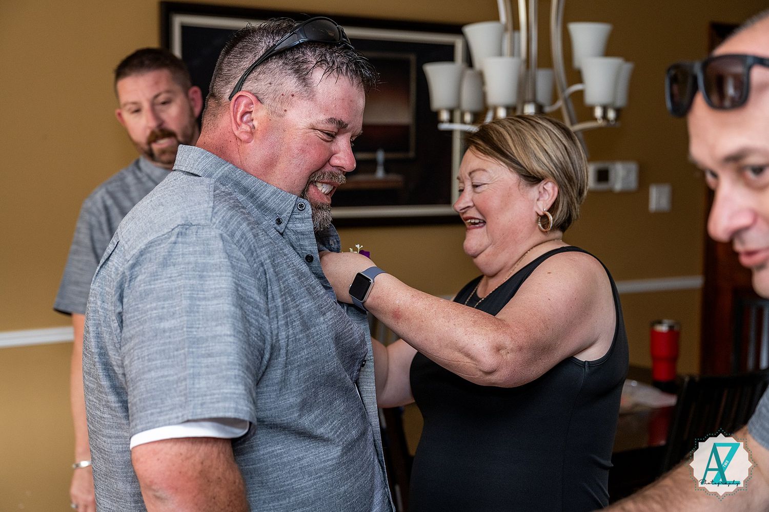 Two people have a heartfelt embrace as others look on during an emotional indoor gathering.
