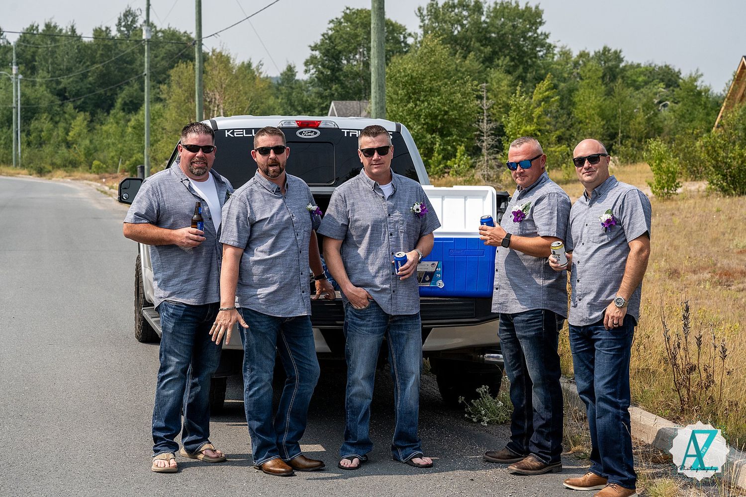 Group of workers in matching uniforms stand together outside near utility vehicle on bright sunny day.