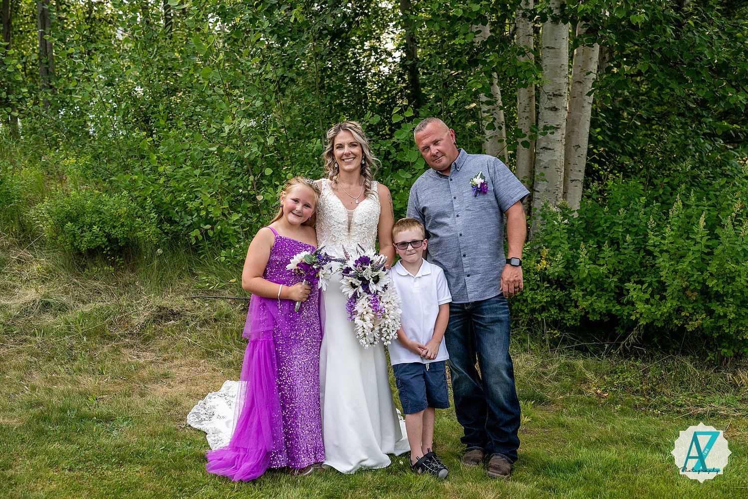 People pose together on grass with trees in background during outdoor celebration.