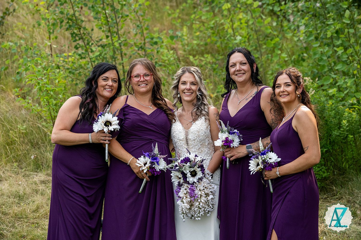 Bridesmaids wearing deep purple dresses pose for a series of wedding photos in a lush garden setting with white bouquets.