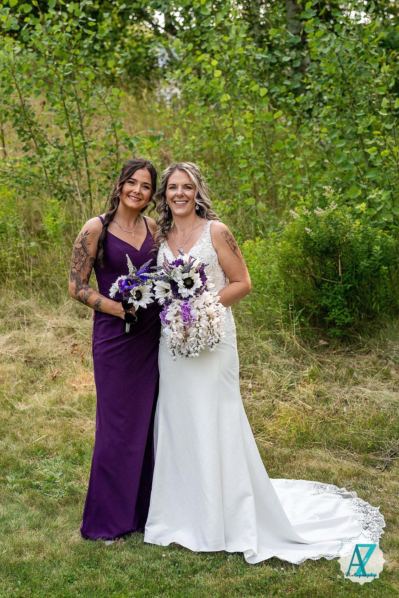 A wedding party in a garden setting with a purple bridesmaid dress and white bridal gown holding floral bouquets.